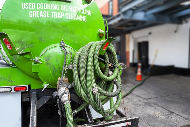 a professional plumber using a pump to empty a grease trap in Barrington